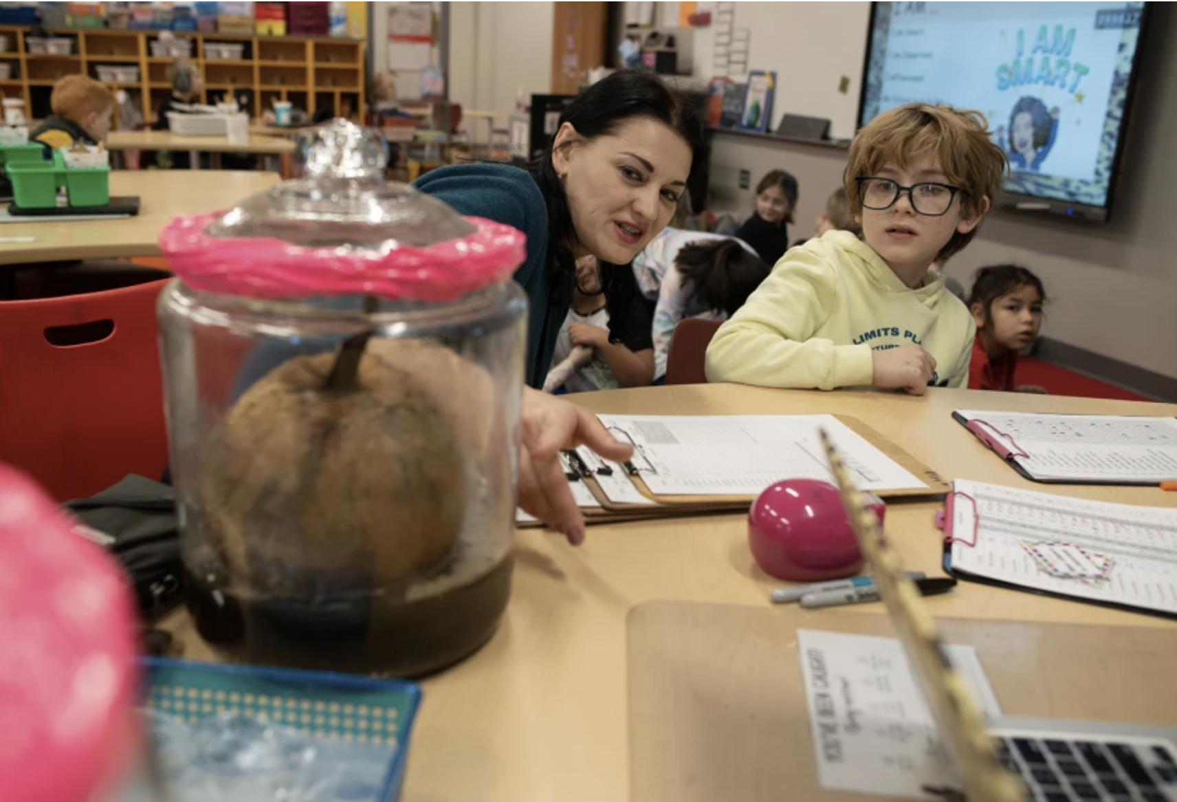  Paraeducator Nataliia Mostova demonstrates pumpkin molding to Adrian Karmalita in a 2nd grade classroom at Jardine Elementary School in Topeka, Kansas. Mostova, a refugee from Ukraine, is working at the school to support her family and provide additional support to students. Photo credit: Evert Nelson for Education Week. 